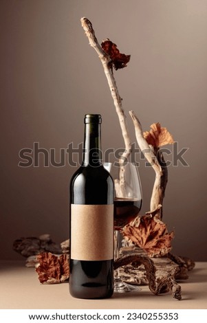 Bottle and glass of red wine with a composition of old wood. Minimalistic composition on a beige background for product branding, identity, and packaging. Copy space.