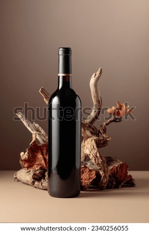 Bottle of red wine with a composition of old wood. Minimalistic composition on a beige background for product branding, identity, and packaging. Copy space.