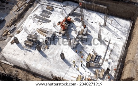 Aerial Top Down View on a Constructions Site with Team of Workers. Heavy Crane and Construction Workers are Working. High quality photo