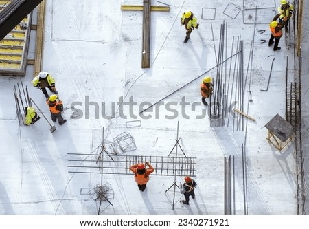 Workers in orange and yellow robes doing their job at the construction site. Top view. High quality photo