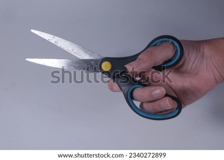 Hand holding scissors isolated on a white background, open scissor ready to cut