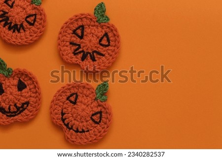 Crochet Halloween pumpkins on an orange background. Handmade Halloween decor. Copy space. Top view.