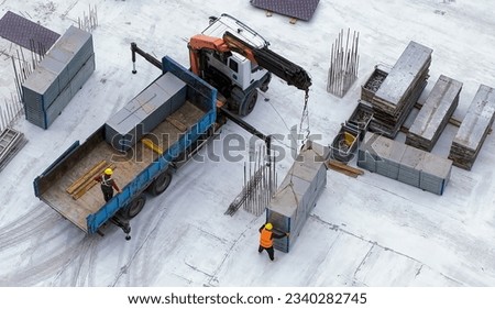 Truck crane uploading a concrete block at the construction site. Workers around. Gray background. Top view. Daylight. High quality photo