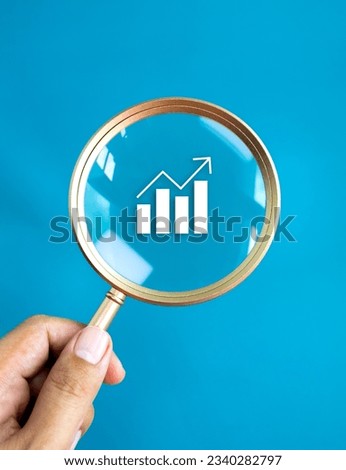 Business analytic chart, growth graph icon in round lens of luxury gold magnifying glass in businessman's hand isolated on blue background. Trends searching, money stock analysis, investment concepts.