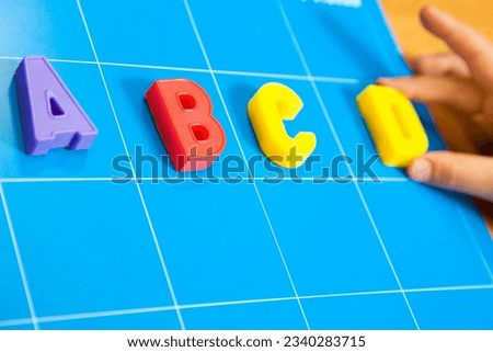child learning the ABC-s. The focus is on the letter B