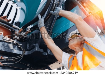 Mechanic repairing hydraulic hose in drilling machine, exploration drilling. Man in hard hat industrial worker. Royalty-Free Stock Photo #2340286919