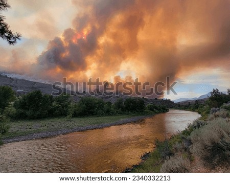 A stunning and erie photo of wildfire smoke fulling the sky as it reflects off the river Royalty-Free Stock Photo #2340332213
