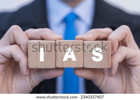 Accountant holding colorful blocks with icons and abbreviation: IAS. Concept of IAS International Accounting Standards. Financial statements.