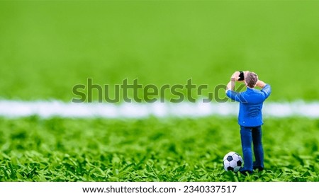 a small toy man takes pictures of the grass of the football field
