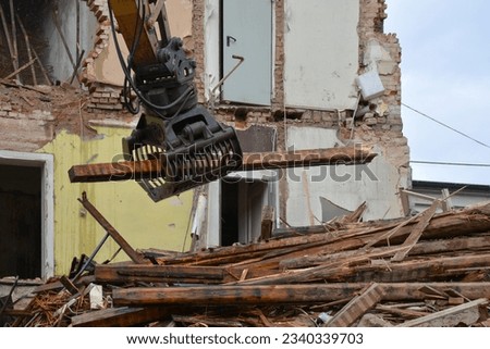 Excavator manipulator disassembles wooden beams during the dismantling of an old building. Dismantling the city's housing stock for renovation