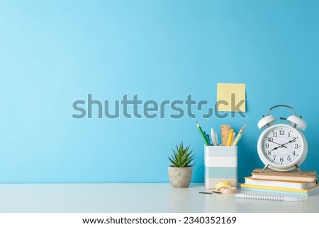 Student's workplace concept. Side view photo of white desk with alarm clock, notepads, penholder and office supplies on blue isolated background with copy-space for text or advert Royalty-Free Stock Photo #2340352169