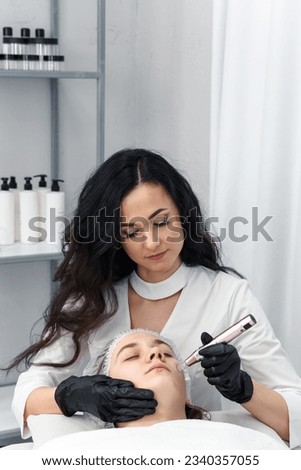 cosmetologist making mesotherapy injection with dermapen on face for rejuvenation. Anti-aging treatment and face lift in cosmetology clinic. medical procedure with Electric pen for derma stamp Royalty-Free Stock Photo #2340357055