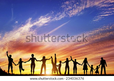 Happy group of diverse people, friends, family, team standing together holding hands and celebrating success. Sunset sky