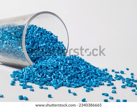cold cut type blue pearlish masterbatch granules with glass cup in white background photo. This material is a coloring agent for products of the plastics industry Royalty-Free Stock Photo #2340386665