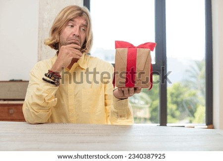 young adult caucasian man smiling with a happy, confident expression with hand on chin. gift concept