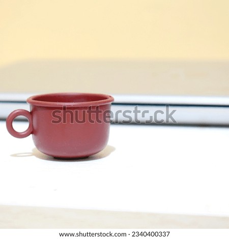 Square picture with mug object and lapop on white table, with slow light dim, soft light yellow white