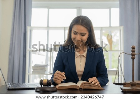 Asian female lawyer in formal dress Work with laptops and law books, hammers and scales, real estate work and dispute contract documents for defense strategies. Fight for freedom 