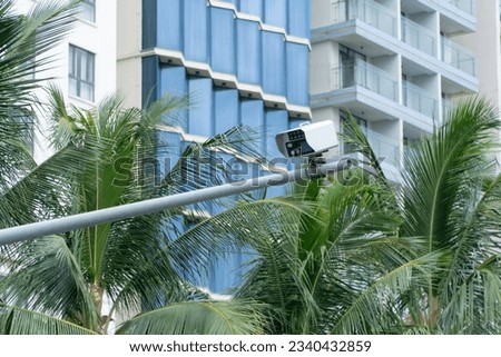 Surveillance camera of a street with coconut tree background and building behind.  Tracking concept, street security.