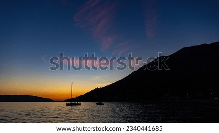 colorful sunset in orebić harbor, peljesac peninsula, croatia; dark silhouettes of yachts and boats with red sunset in the background	