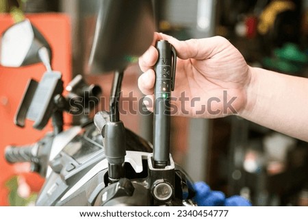 Technician checks brake fluid in motorcycle with Brake Fluid Liquid Tester Quality Check Pen Tool at garage, motorcycle maintenance and repair concept Royalty-Free Stock Photo #2340454777