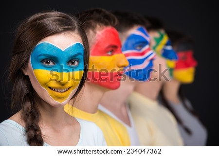 International team. Five  young people with national flags painted on the faces.