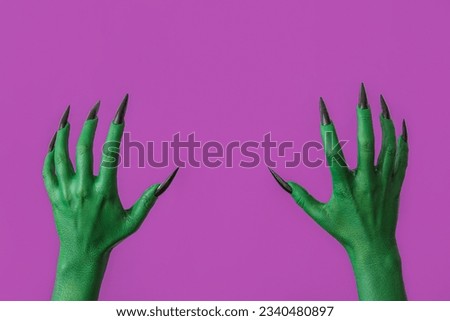 Green hands of witch on purple background. Halloween celebration