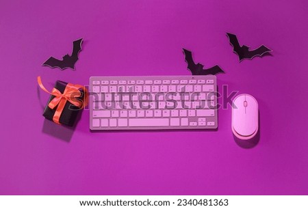 Composition with modern computer keyboard, mouse, gift box and paper bats for Halloween on purple background