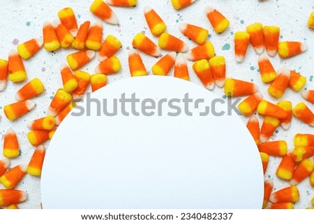 Composition with tasty Halloween candy corns and blank card on light background, closeup
