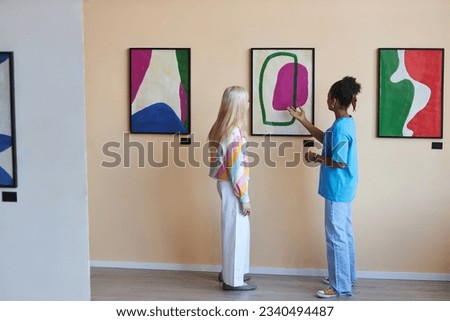 Minimal full length portrait of two teenagers girls discussing modern art in gallery or museum, copy space