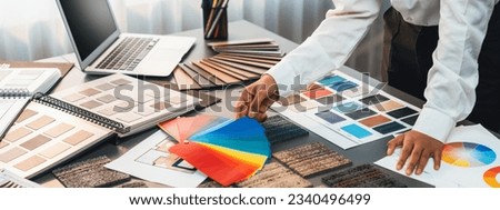 Interior architect designer at workstation table choosing various color samples art tool design with home blueprint. Creative color selection for house renovation or design concept. Insight