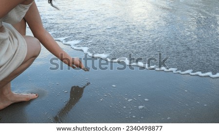 woman drawing heart shape on sea sand
