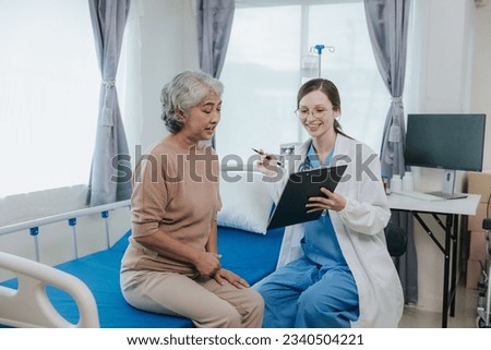 Young beautiful smiling doctor nurse caring to help happy senior grandmother helping old patients in rehabilitation at elderly health checkup Royalty-Free Stock Photo #2340504221