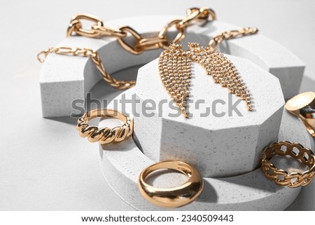 Decorative podiums with beautiful jewellery on grey background Royalty-Free Stock Photo #2340509443