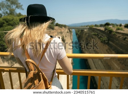 Woman photographer with backpack taking photo of Corinth canal.Travel and hobby concept 