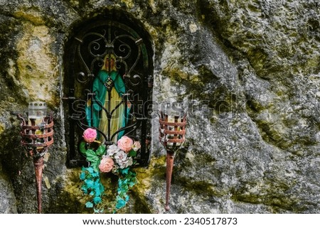 wayside shrine with flowers and candles in a rocky wall during hiking in the mountains