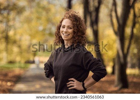 Portrait of cheerful caucasian woman wearing sports clothes and standing in the autumn park Royalty-Free Stock Photo #2340561063