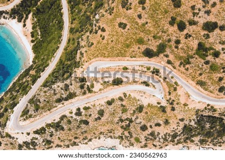Windy road along coast of Aegean sea, aerial top down view Royalty-Free Stock Photo #2340562963