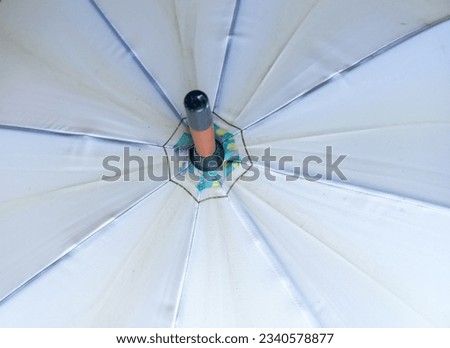 Upper part of an open white umbrella with radial line pattern.
