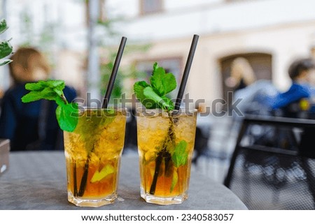 Alcohol drink. On Table cafe outdoors. glasses with alcohol drink and half lime,mint leaves. cocktail mojito with slice lime and mint leaf. City life.Blurred cafe background.Summer evening.