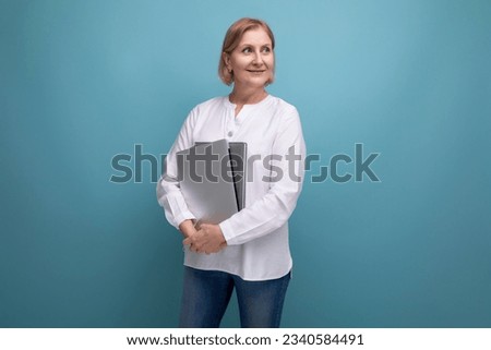 serious mature business woman with blond hair works on internet using laptop