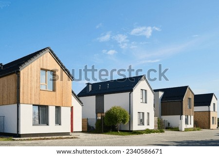 Perspective view of several small houses standing in row in rural environment against blue sky on sunny day