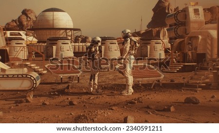 Two astronauts in spacesuits walk toward research station, colony or scientific base on Mars. Solar cell and panels. Space mission on red planet. Futuristic colonization and space exploration concept. Royalty-Free Stock Photo #2340591211