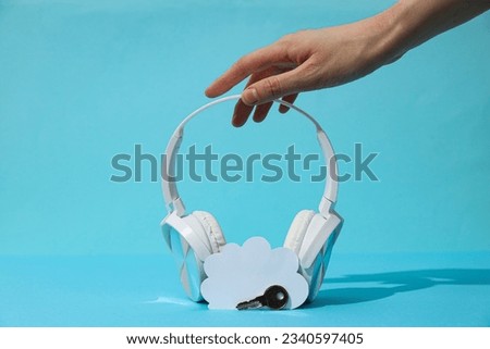 Full size headphones with white paper cloud and key on blue background