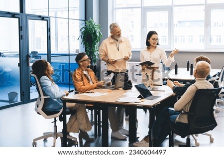 Group of happy male and female entrepreneurs collaborating on startup project during gather business meeting, successful colleagues talking about marketing planning during brainstorming Royalty-Free Stock Photo #2340604497