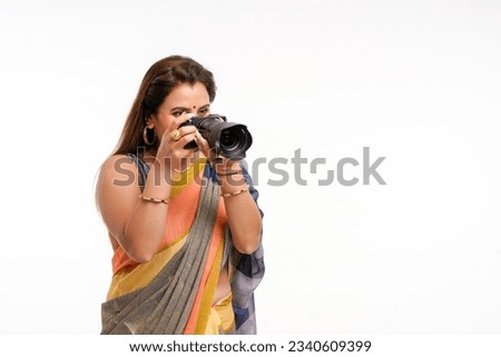 Indian woman in traditional sari and using camera on white background.
