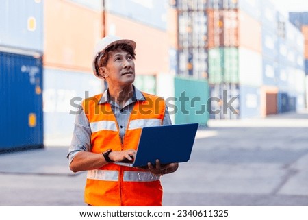 Foreman in uniform wearing safety helmet using laptop checking containers loading. Area logistics import export and shipping cargo freight ship. Royalty-Free Stock Photo #2340611325