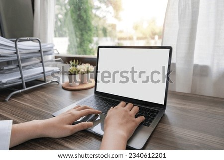 Woman hands typing on the laptop with empty blank white screen mockup. Computer is laying on the table. Person working from home concept. Copy space area for text