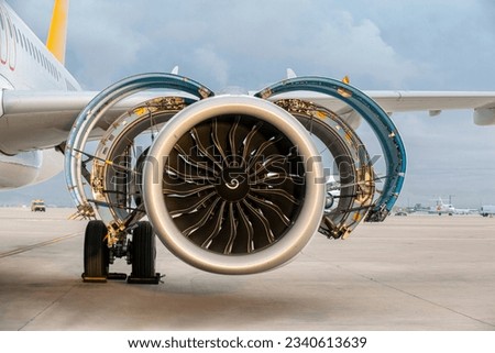 Jet engine. A modern, new generation, jet-powered passenger aircraft is waiting at the airport. Aircraft parked with open hatches for jet engine maintenance. Royalty-Free Stock Photo #2340613639