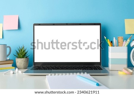 Create engaging online education content with a side view picture of a white desk, laptop, and stationery on an isolated blue background, providing copy-space for text or advertising