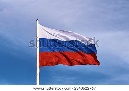 Large flag of the Russian Federation on a flagpole 75 meters high. Technological device with wind speed sensors and automatic flag height adjustment system. Blagoveshchensk, Far East, Russia. Close up Royalty-Free Stock Photo #2340622767
